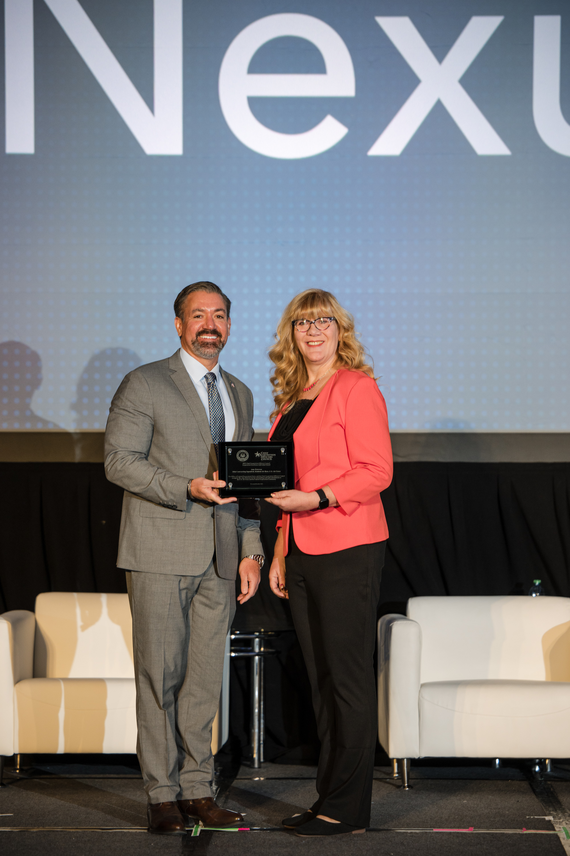 Dr. Kevin Rhodes, Administrator of the Office of Federal Procurement Policy (left), presents Amy Petersen (right), with the Acquisition Excellence Individual Award.